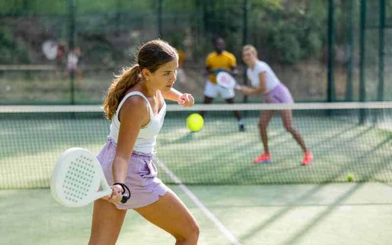 Young woman playing padel at Melbourne academy with teammates.
